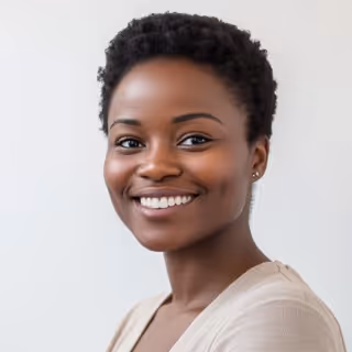 Smiling woman with short curly hair wearing a light beige top against a plain light background.